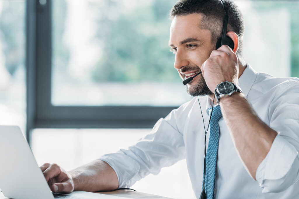 smiling adult support hotline worker with laptop at workplace
